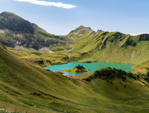 kristallblauer Bergsee, genannt Schrecksee mit kleiner Insel in der Mitte, im Grenzgebiet der österreichischen und allgäuer Alpen.