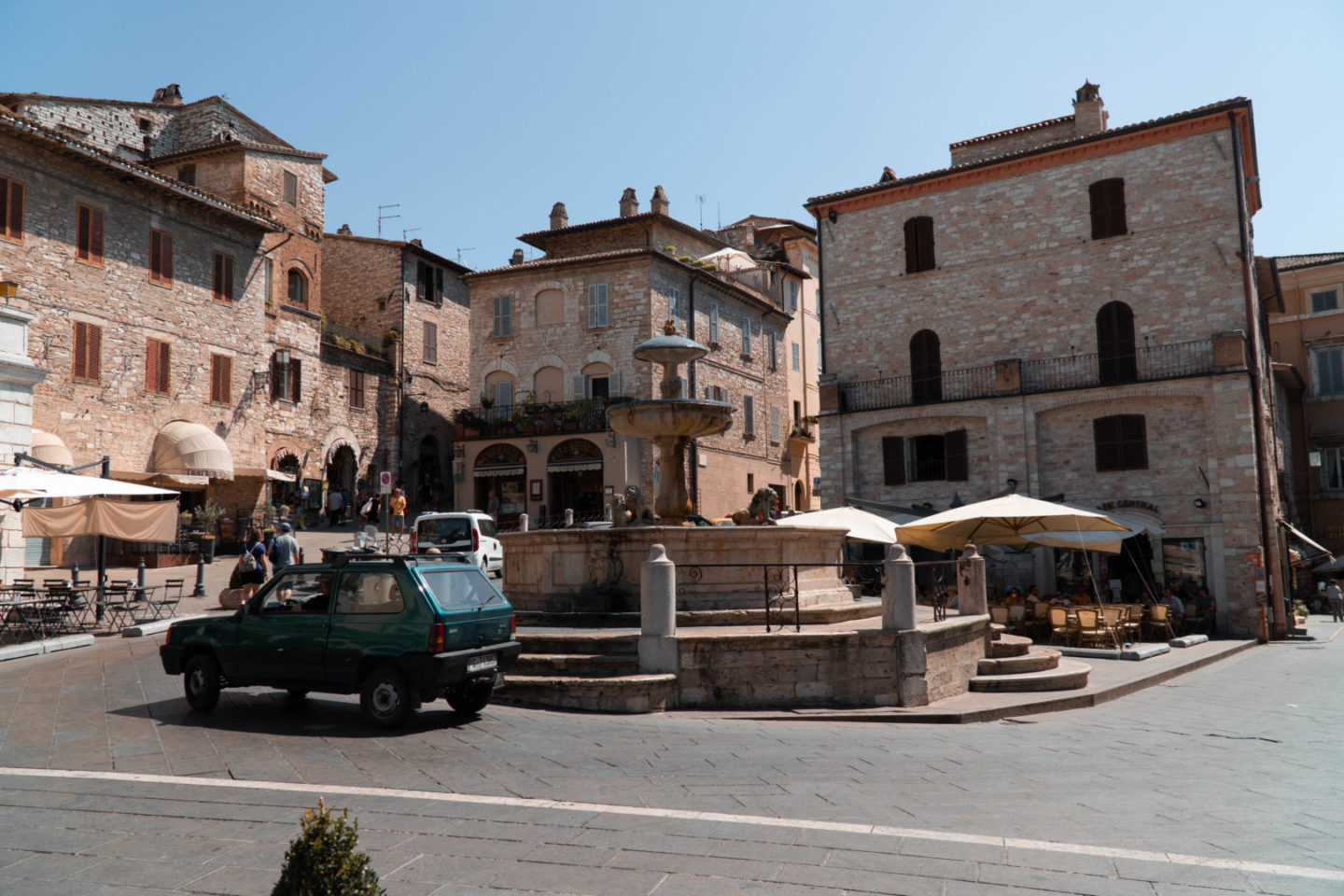 Altstadt von Assisi mit italienischem Auto und Sonnenschein.