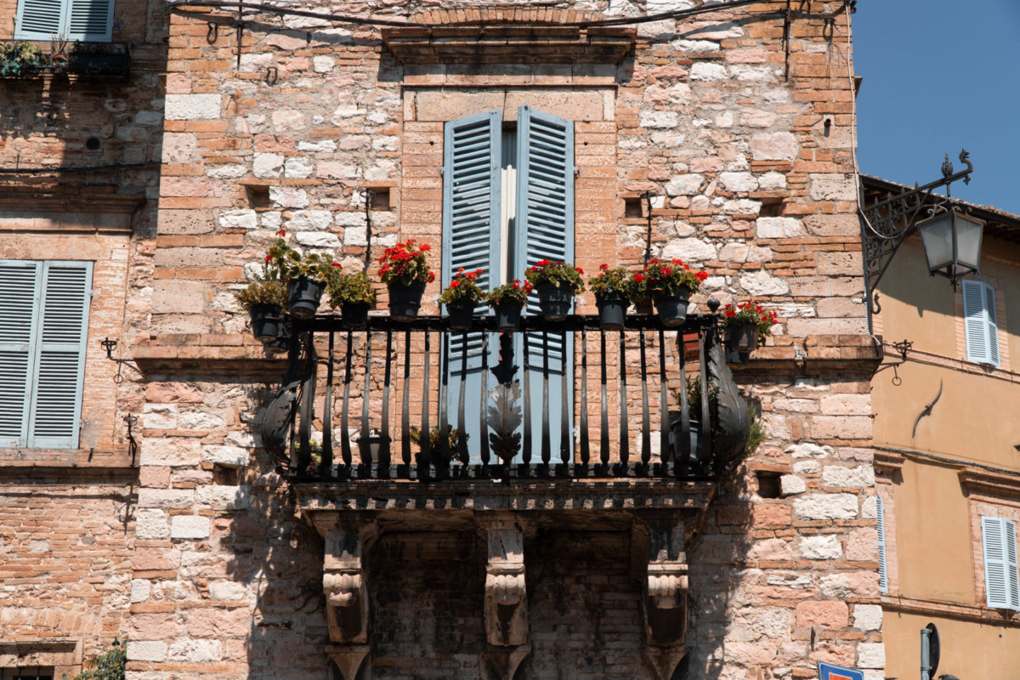 Balkon mit blauen Fensterläden von umbrischen Stadthaus in der Franziskusstadt Assisi.